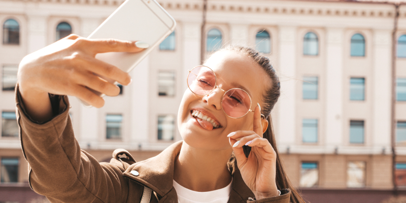 mulher de oculos com um celular na frente do seu rosto